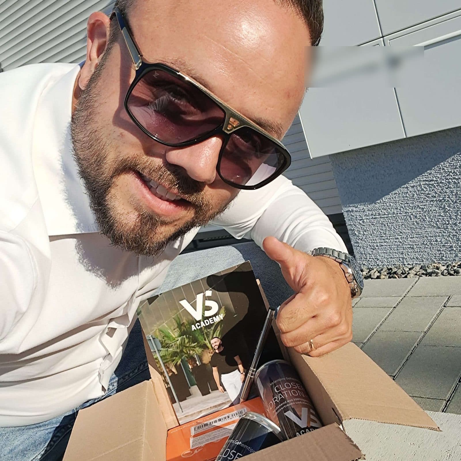Teilnehmer mit Daumen hoch und geöffnetem Paket vor den Briefkästen